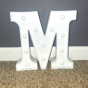 A light up letter M. Can be hung up it placed on a shelf, dresser, table ext.